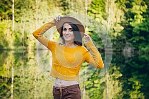 Woman stands on a bridge on a lake with an autumn landscape