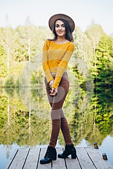 Woman stands on a bridge on a lake with an autumn landscape