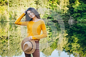 Woman stands on a bridge on a lake with an autumn landscape