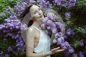 Woman stands among the bushes blooming lilac