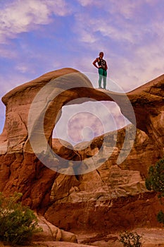 Woman Stands on Curved Arch in Escalante