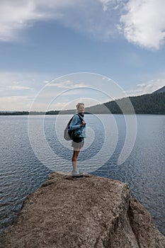 Woman Stands on Edge of Large Boulder Along Phelps Lake