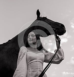 Woman stands and holds horse by bridle