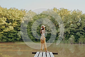 A woman stands on a lake bridge and looks out at the beautiful view in yellow pants in the fall. High quality photo