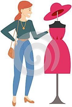 Woman stands near mannequin in ready-made dress. Lady designer looks at outfit, work of fashion art