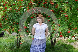 Woman stands near rowan in the summer