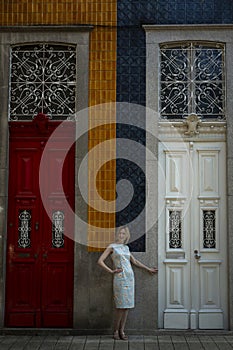 A woman stands near the tall doors of a traditional Portuguese house in Porto.