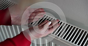 Woman stands by radiator enjoying sensation of warmth