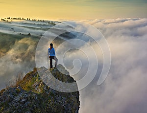 woman stands on a rock above a river canyon. female tourist enjoys foggy autumn landscape