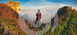 woman stands on a rock above a river canyon. female tourist enjoys foggy autumn landscape