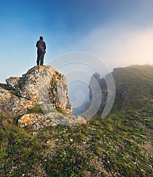 woman stands on a rock above a river canyon. female tourist enjoys foggy autumn landscape