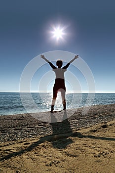 Woman stands on socks ashore opposite sun
