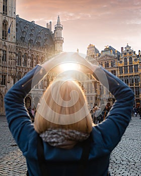 Woman stands in the square Grand Place in Brussels, Belgium at sunset.