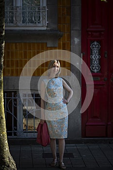 A woman stands on the street in a summer dress, Porto, Portugal.