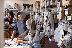 Woman stands to train an apprentice at clothes design studio