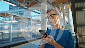 Woman stands at a transport stop and using smartphone.