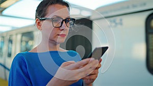 Woman stands at a transport stop and using smartphone. Slow motion