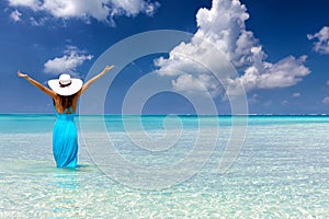 Woman stands in tropical, turquoise waters and enjoys her vacation