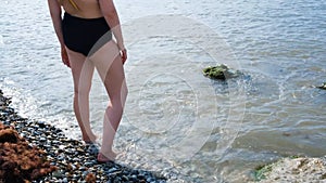 Woman stands and wets feet in water. Concept. Beautiful women`s feet cool in sea during hot summer day. Woman resting on