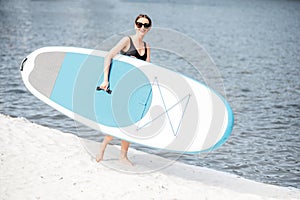 Woman with standup paddleboard on the beach