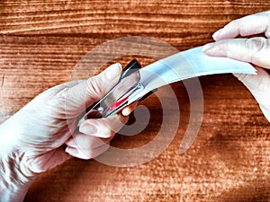 Woman Stapling Papers on a Wooden Desk. A pair of hands using a red stapler to fasten sheets of paper photo
