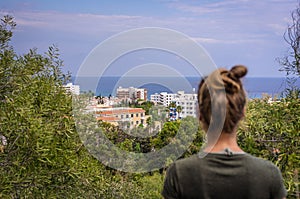 A woman stares into the distance to the sea horizon and the city in front of him