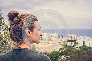 A woman stares into the distance to the sea horizon and the city in front of him