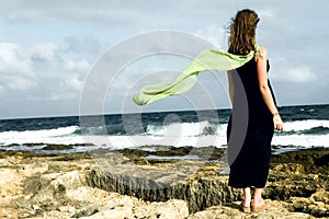 Woman staying on the seashore with shawl behind photo