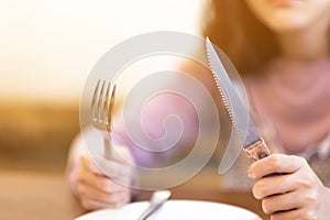 A woman with Steak knife and empty white dish in Steak house,A hungry women waiting for some food