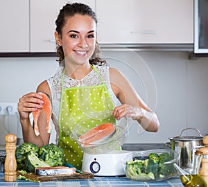 Woman steaming salmon and vegetables