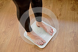 Woman stepping on floor scales indoors, sport and healthy lifestyle. Overweight problem