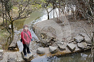 Woman stepping on the stone block across the river