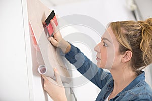 woman sticking adhesive veneer to cupboard