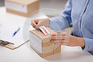 Woman sticking fragile mark to parcel box