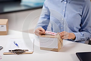 Woman sticking fragile mark to parcel box