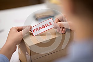 Woman sticking fragile mark to parcel box