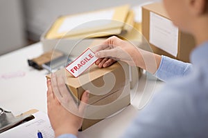 Woman sticking fragile mark to parcel box