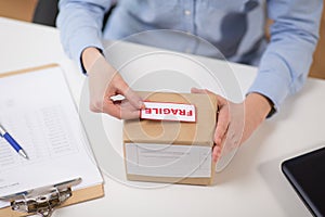 Woman sticking fragile mark to parcel box