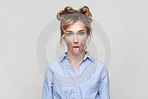 Woman sticking out tongue, misbehaves, demonstrating her disobedience and protest, has funny look.