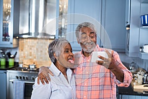 Woman sticking out tongue while taking selfie with man