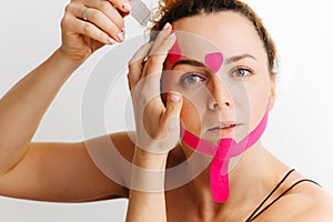 Woman, she sticks a kinesiological tape on her face