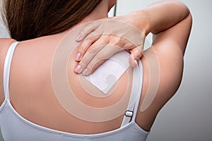 Woman With Stiff Neck Applying Patch photo