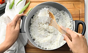 Woman stirring boiled rice in saucepan, closeup