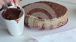 The woman is stirring the chocolate ganache. For chocolate cake with peanuts and strawberries. Close-up shot