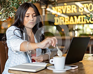 Woman stirring a coffee while working sitting in the coffee shop