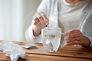 Woman stirring medication in cup with spoon