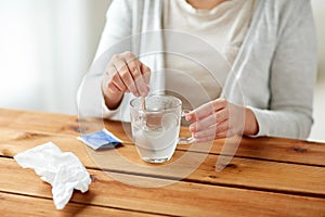 Woman stirring medication in cup with spoon