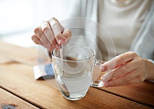Woman stirring medication in cup of water