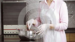 Woman stirring with spoon in saucepan