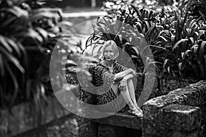 A woman on a stone bench in old parkl. Black and white photo.